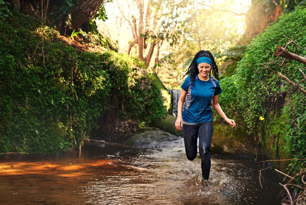 Exercise and have fun while doing it. a sporty young running through a stream of water in nature image