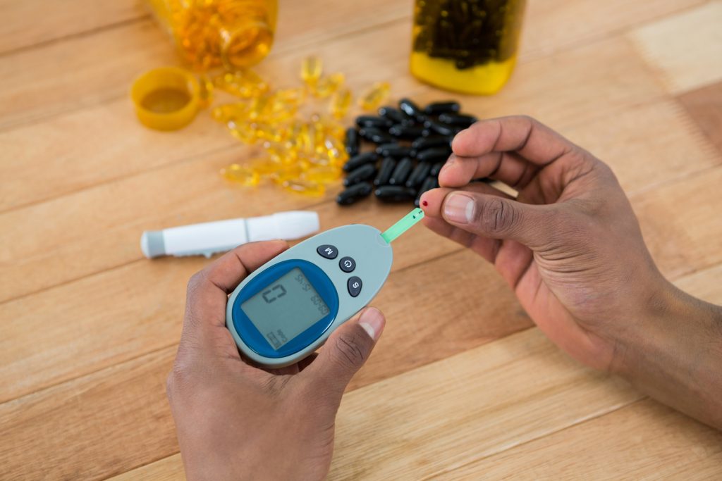 person checking blood sugar with glucometer image.