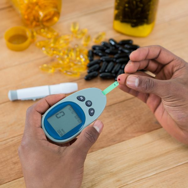 person checking blood sugar with glucometer image.